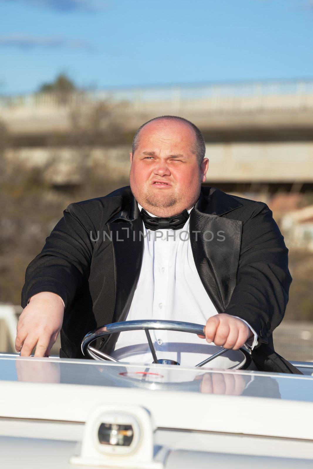 Overweight man in a tuxedo at the helm of a pleasure boat by Discovod