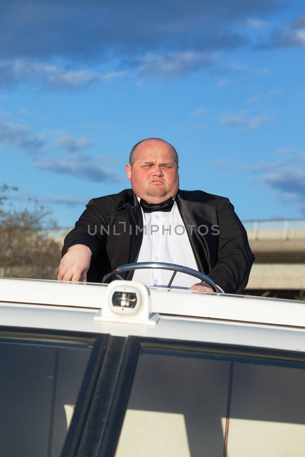 Overweight man in a tuxedo at the helm of a pleasure boat, closeup