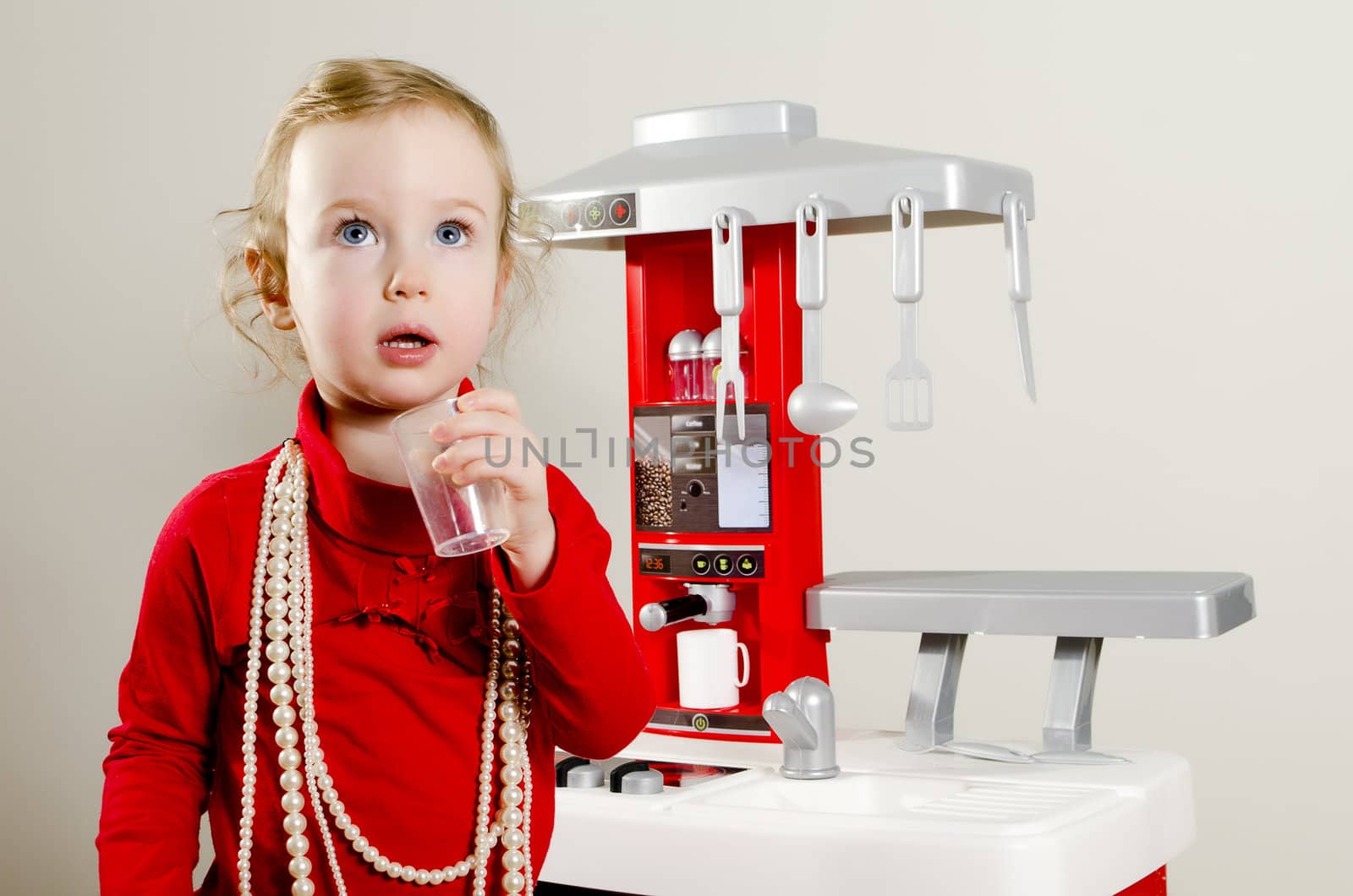Little cute girl playing in children's kitchen.