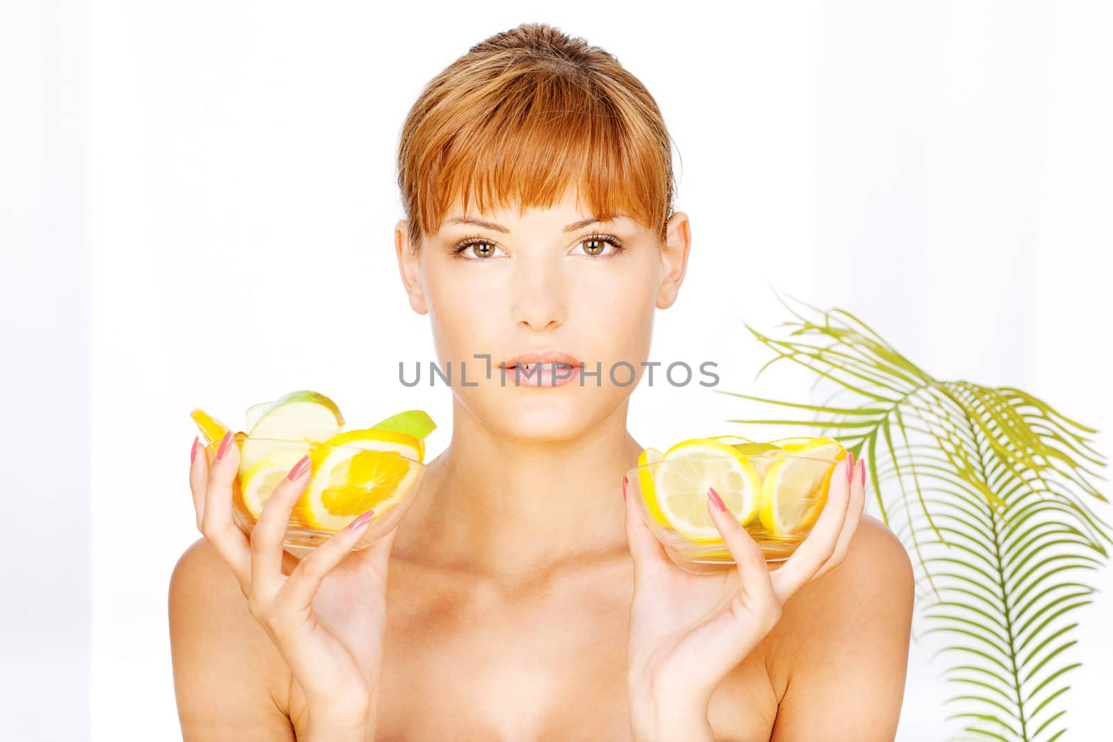 Portrait of a pretty brunette girl with two bowl full of fruit in her hands in a spa salon