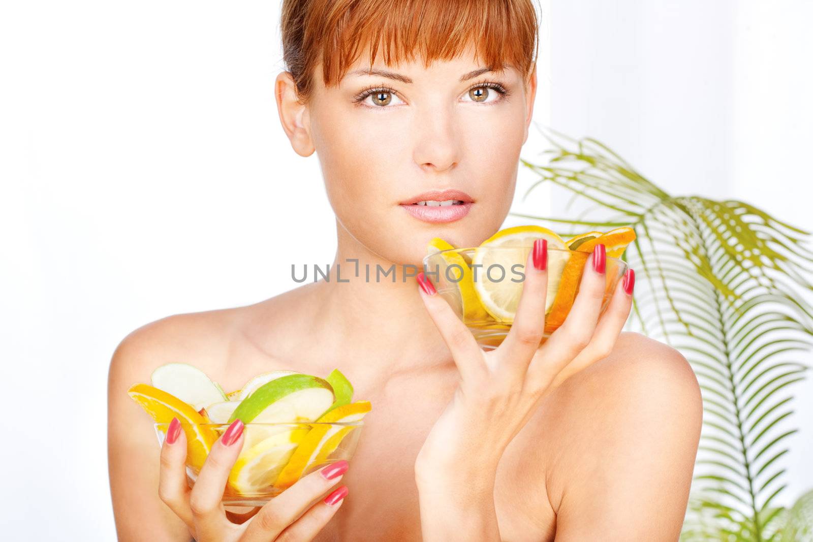 Portrait of a girl in a wellness salon holding two bowls full with fruits, looking at the camera
