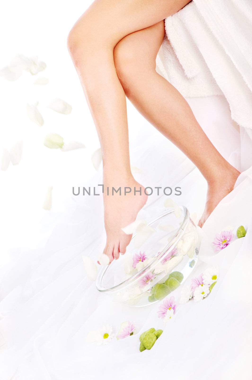 Legs of beautiful girl with aromatherapy bowl and falling petals