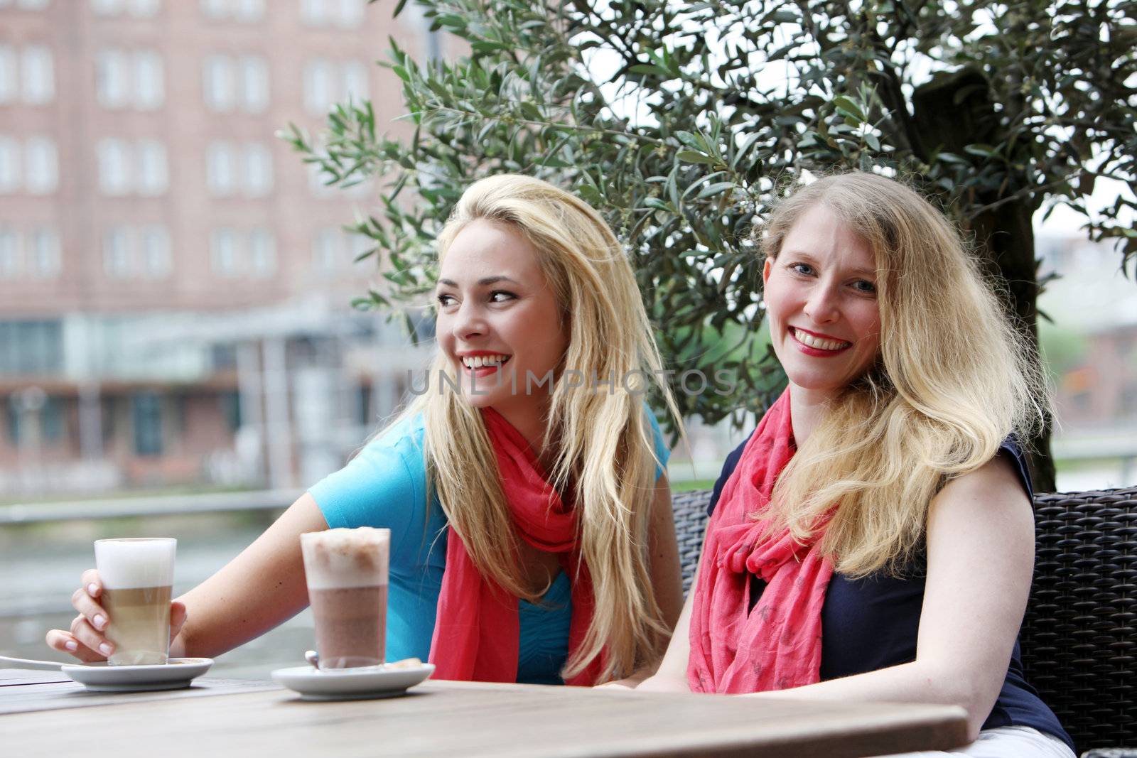 Two attractive professional women unwindng over drinks seated at an outdoor table at an urban restaurant 