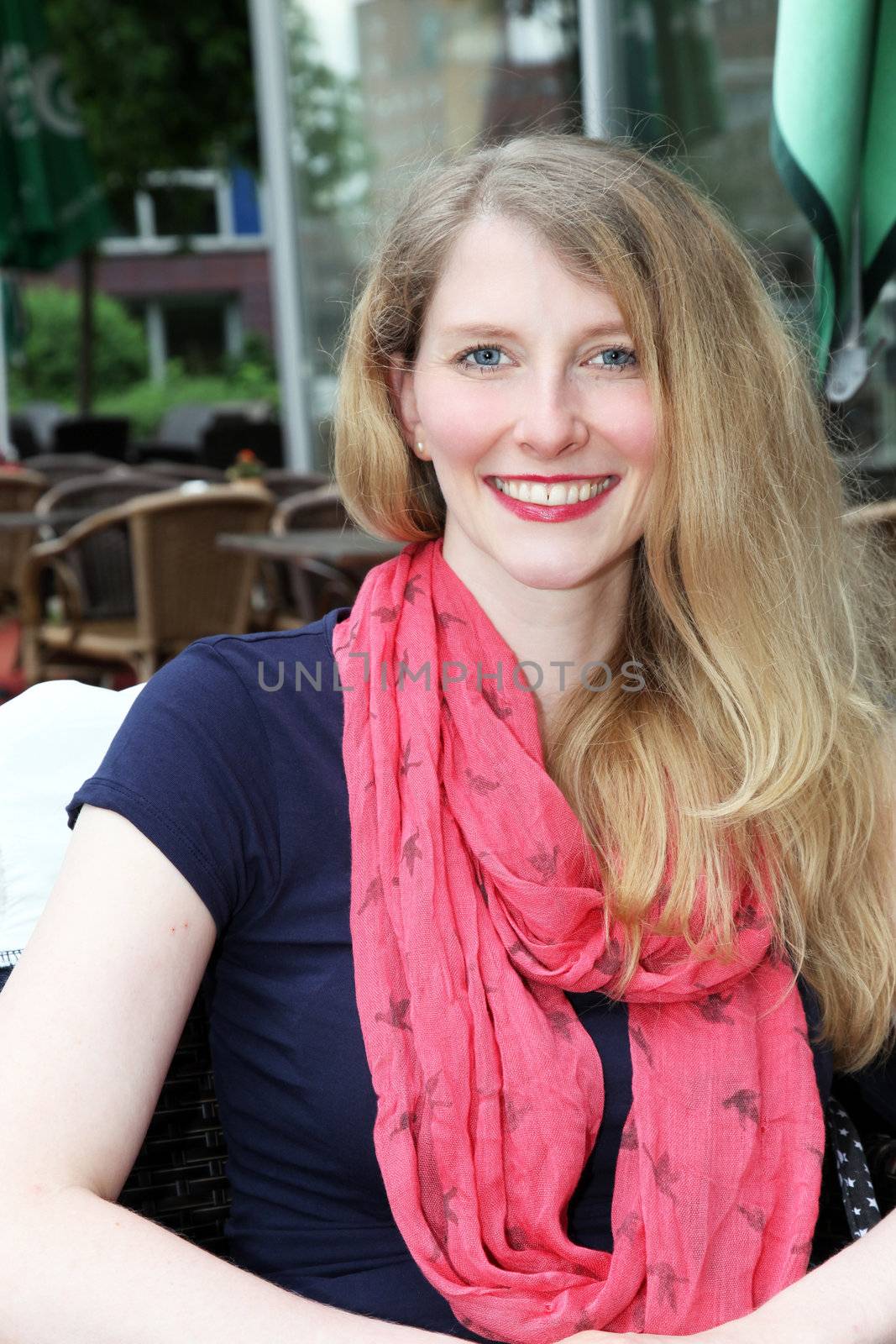 Portrait of beautiful sophisticated lady seated at an open-air restaurant smiling at the camera 