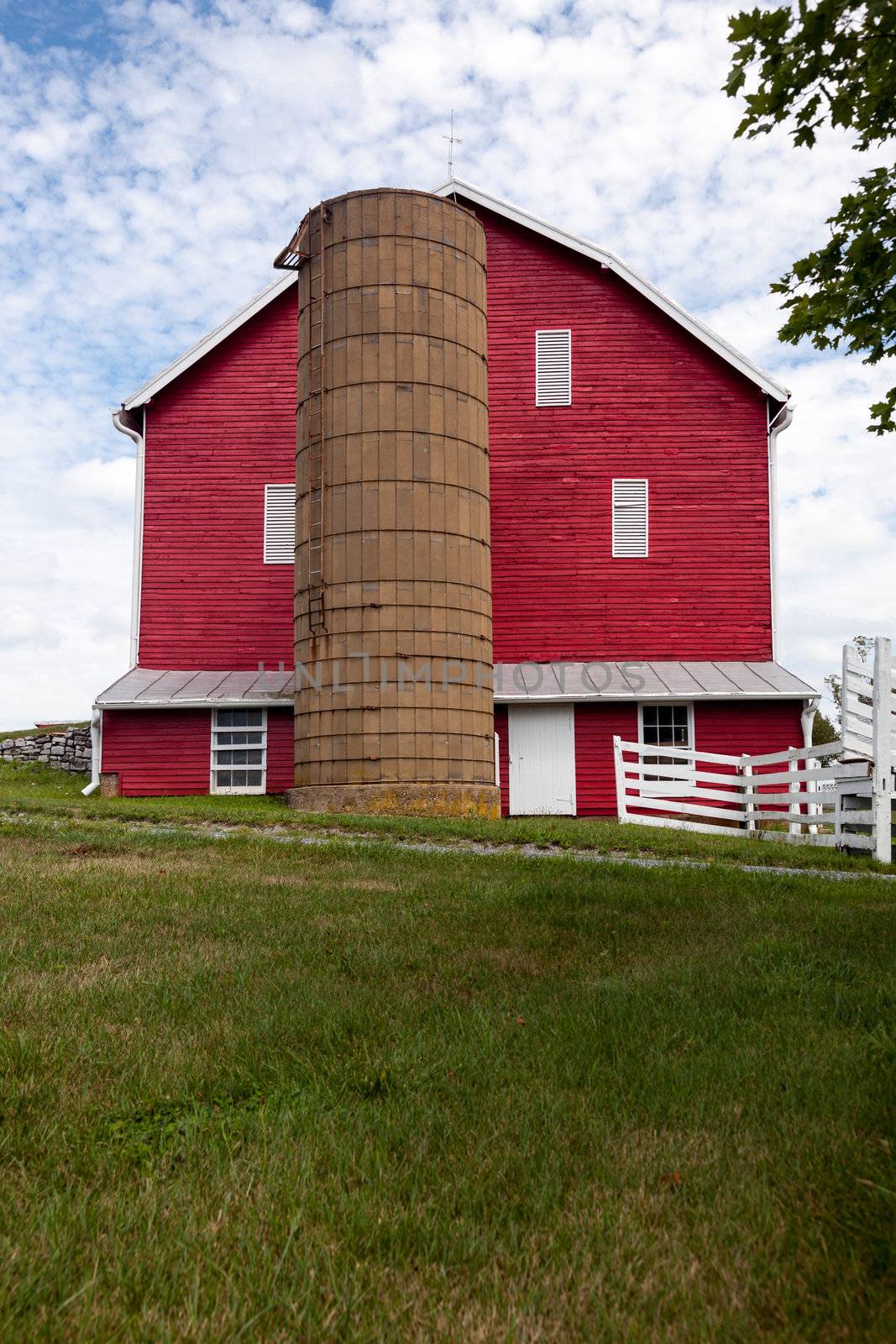 Red painted wooden barn with white door on farm in traditional US style
