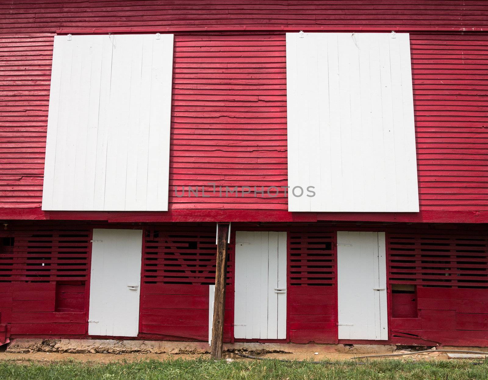 Red painted wooden barn with white door on farm in traditional US style