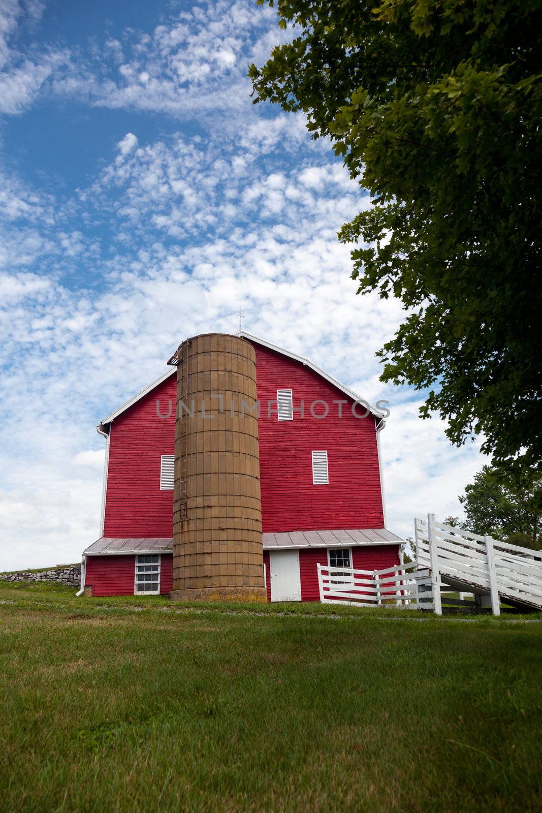 Red painted wooden barn with white door on farm in traditional US style