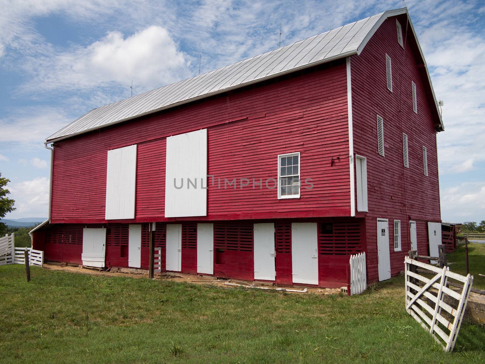 Red painted wooden barn with white door on farm in traditional US style