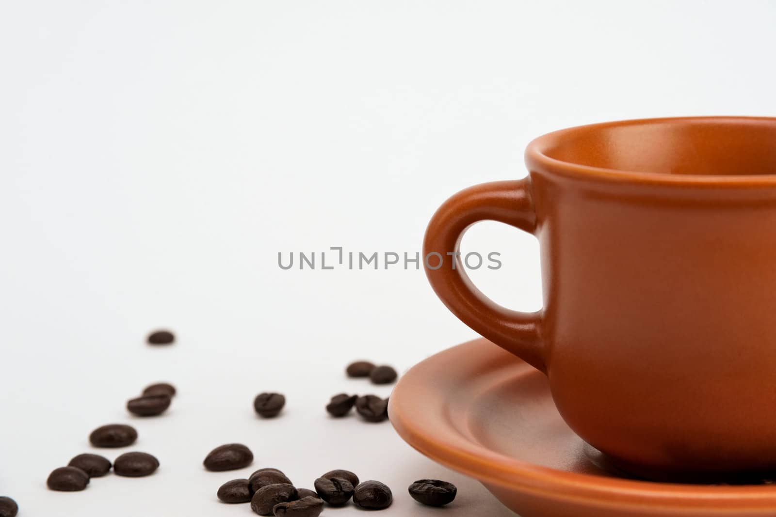 An image of a cup and a saucer with coffee beans