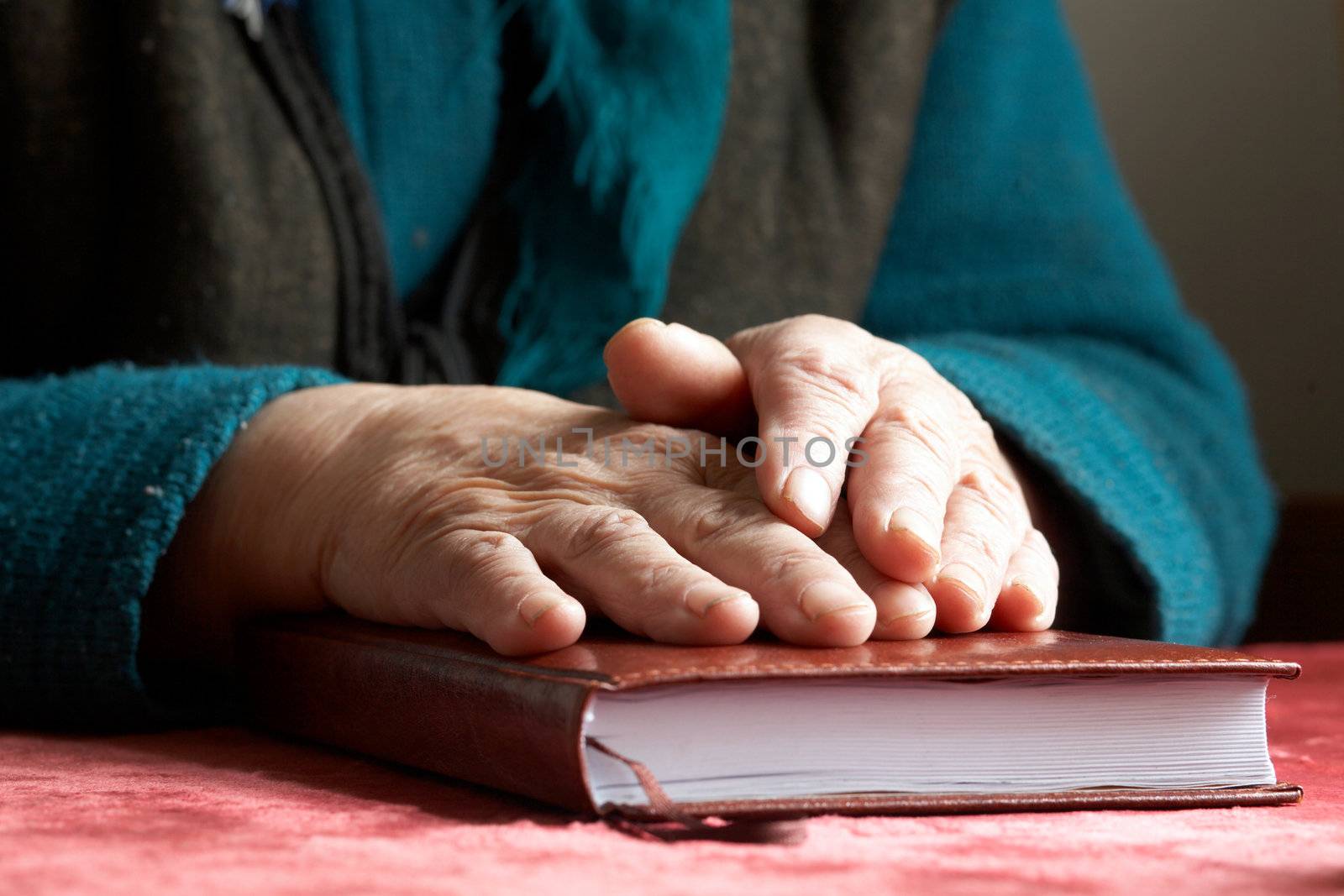An image of old hands on the Bible