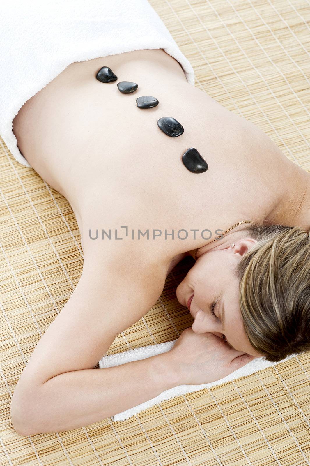Aerial view of woman during hot stone massage. Relaxing with closed eyes