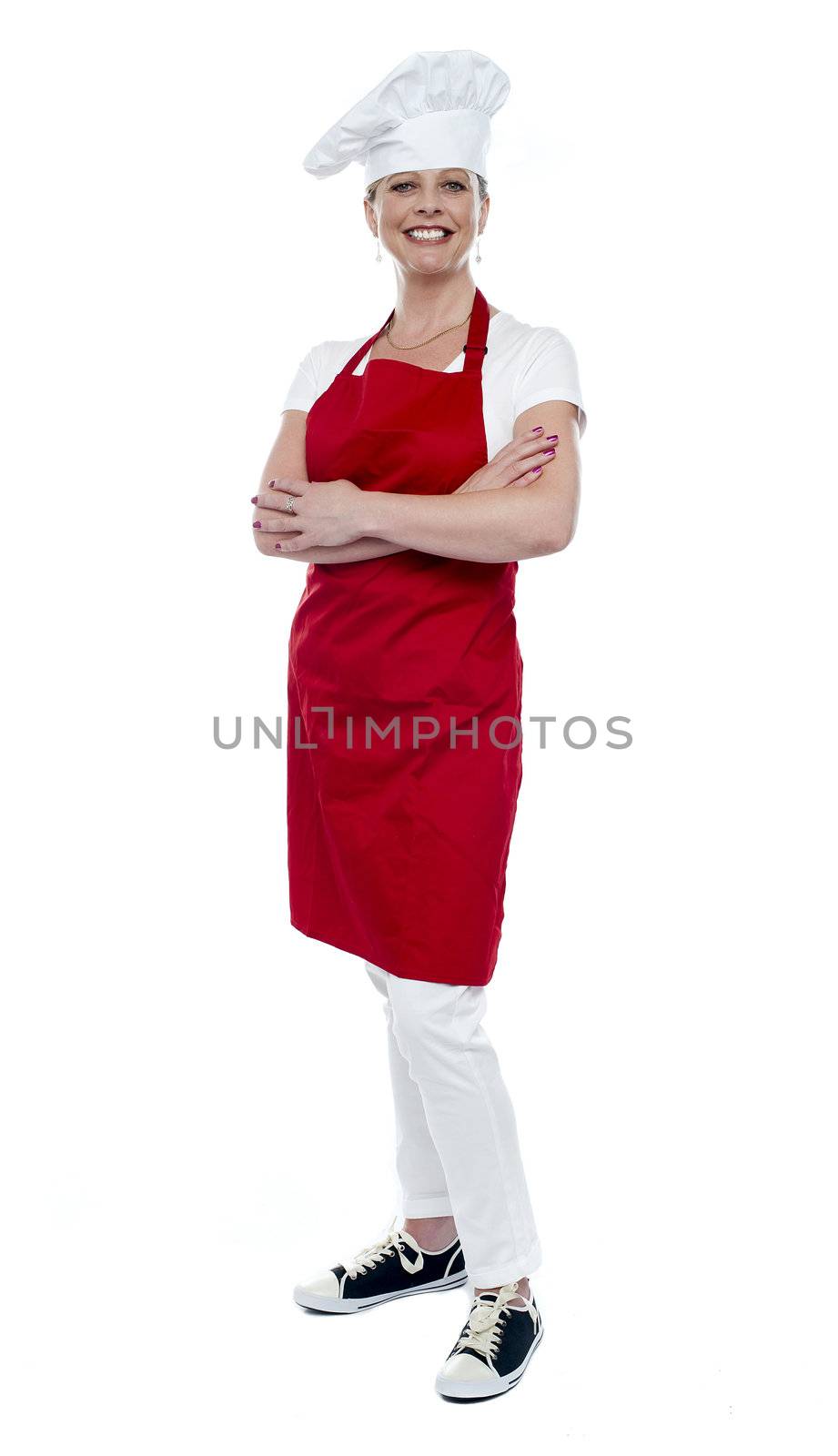 Full length portrait of pretty female cook standing with arms crossed over white