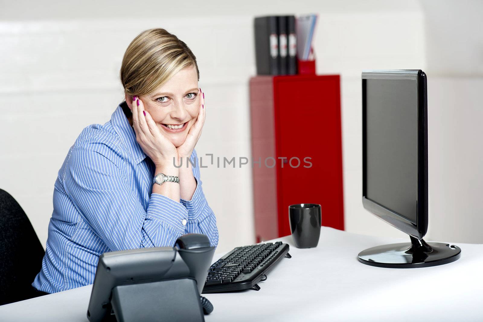 Charming corporate lady posing in office. Sitting with hands on her cheek