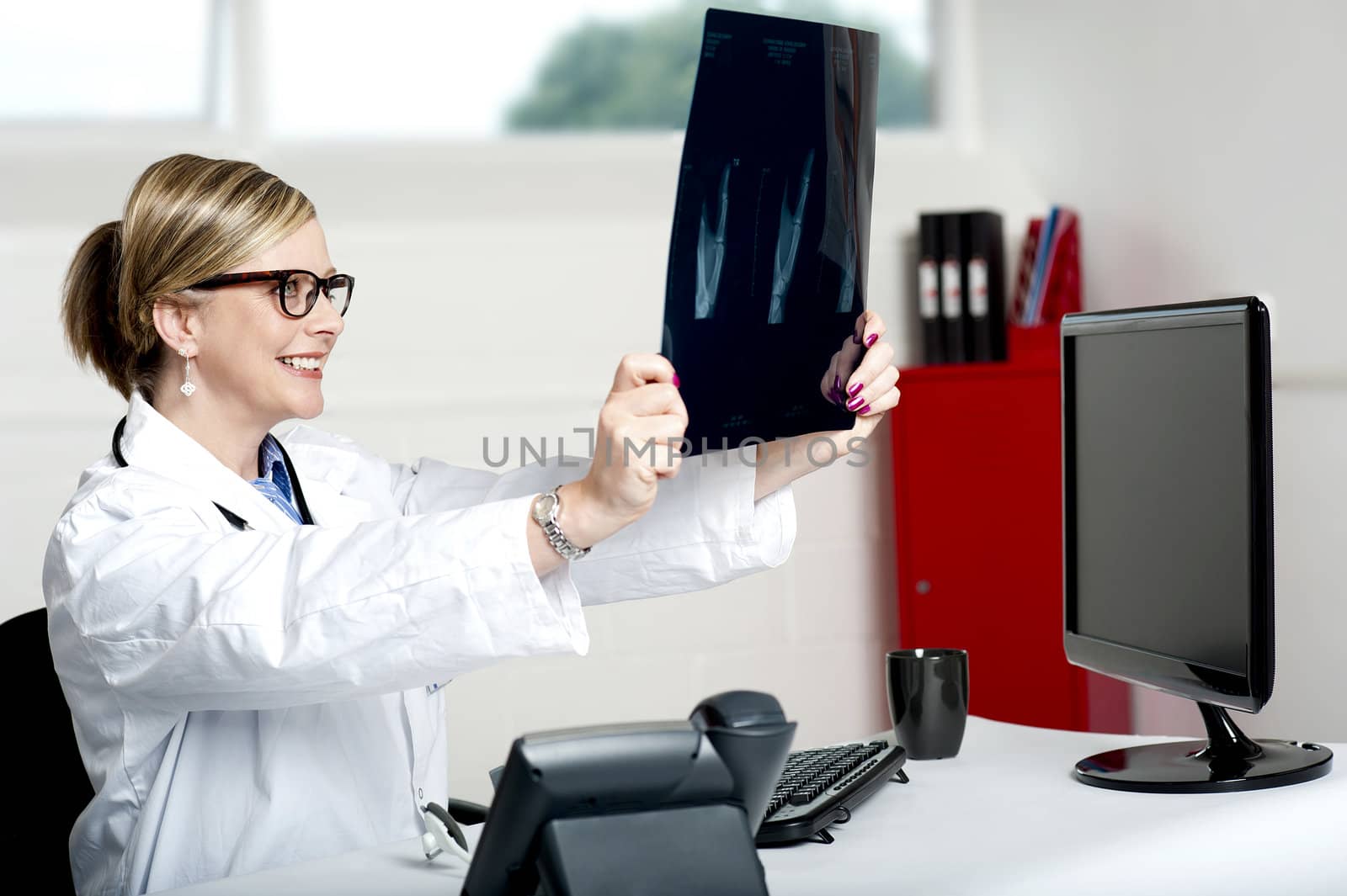 Female doctor looking at x-ray report of patient in clinic. Its good news, she is smiling