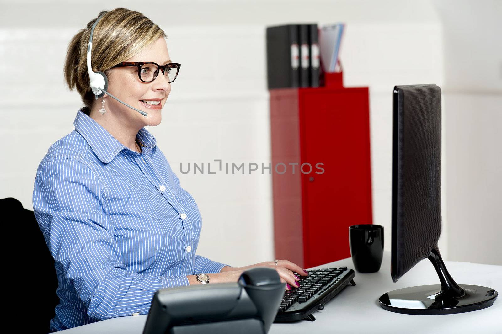 Female executive taking instructions from clients over a call and feeding same on computer