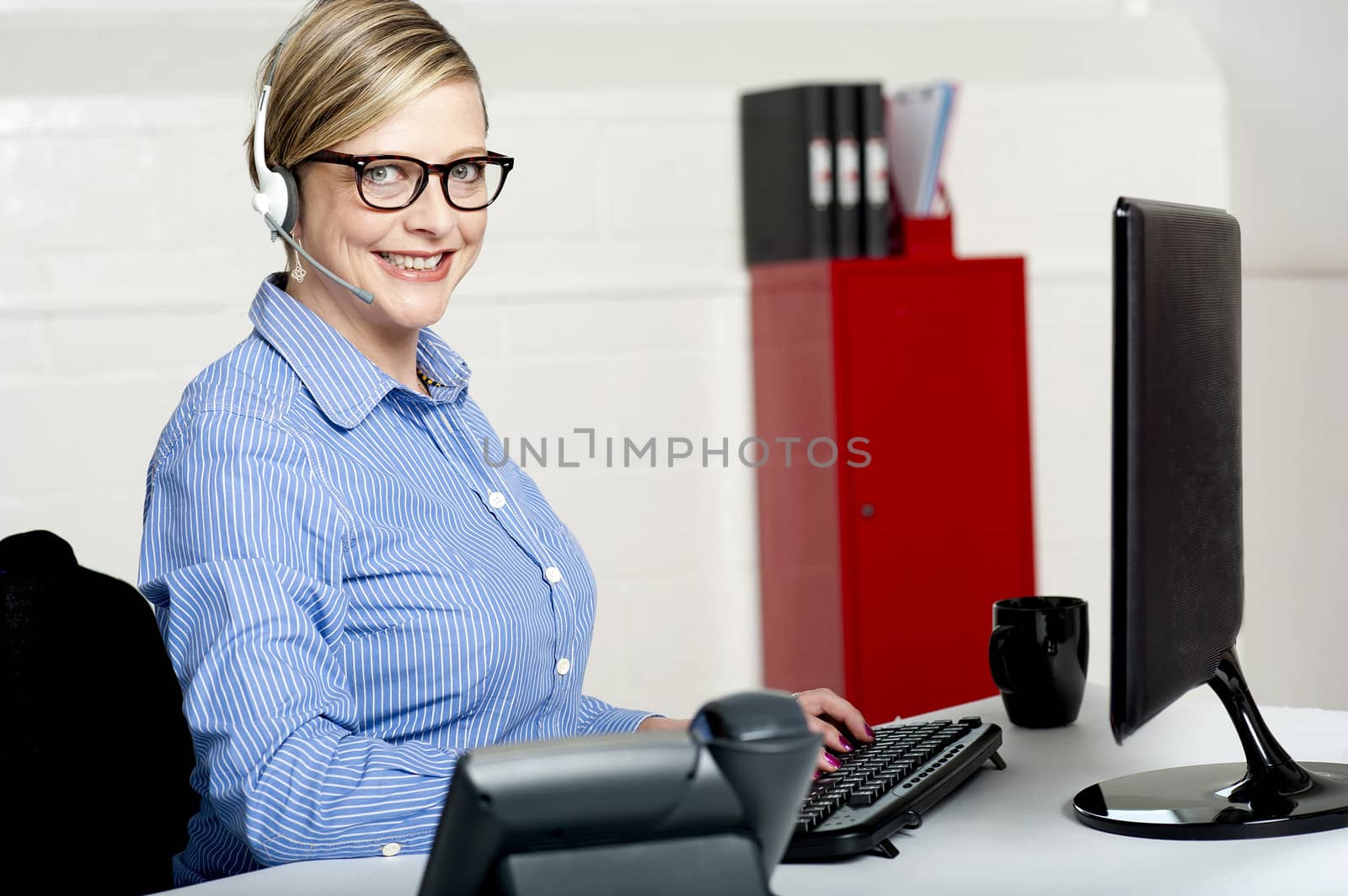 Smiling senior woman sitting in front of computer and working