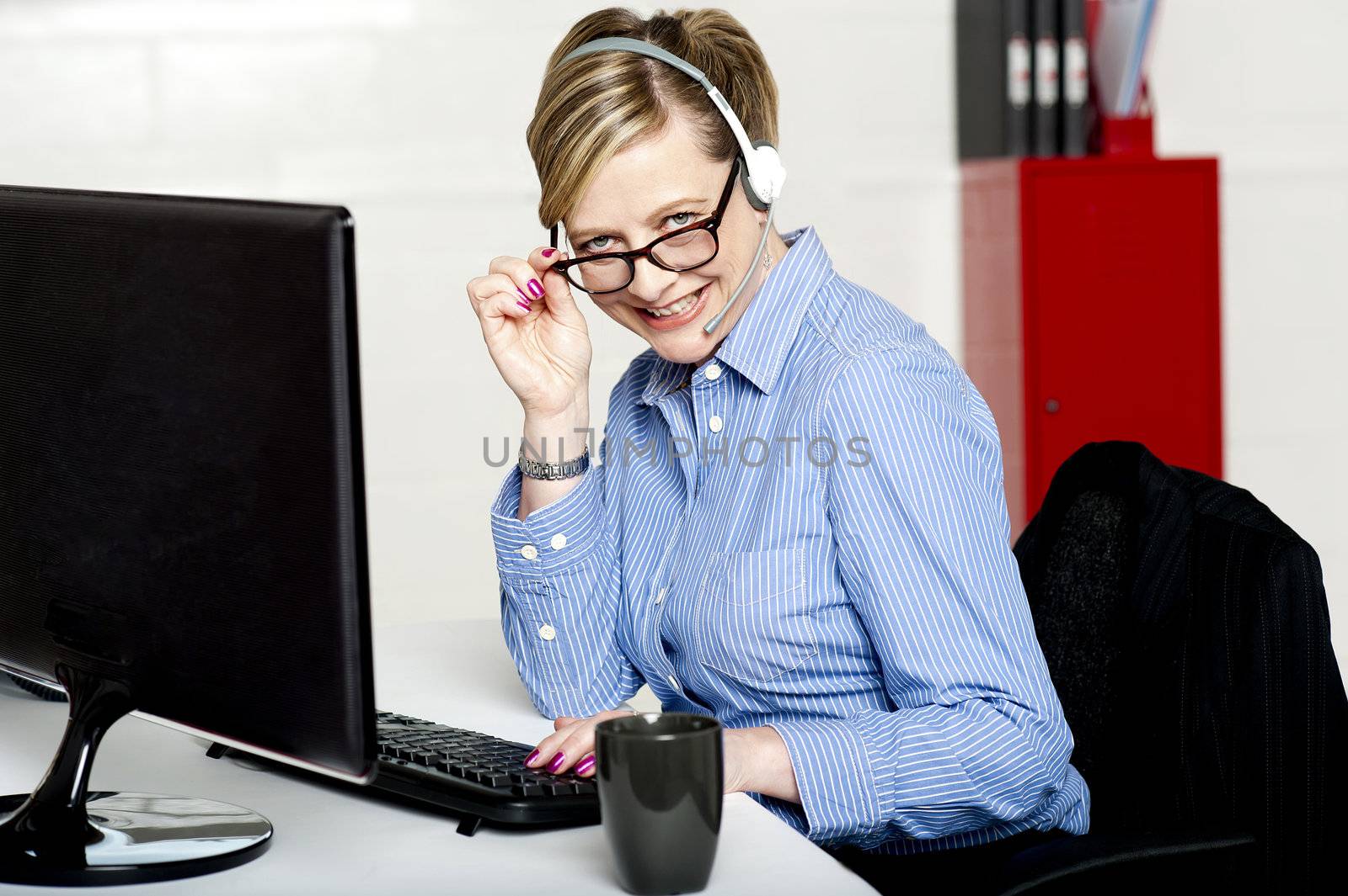 Female call center executive looking at you from behind her eyeglasses and smiling