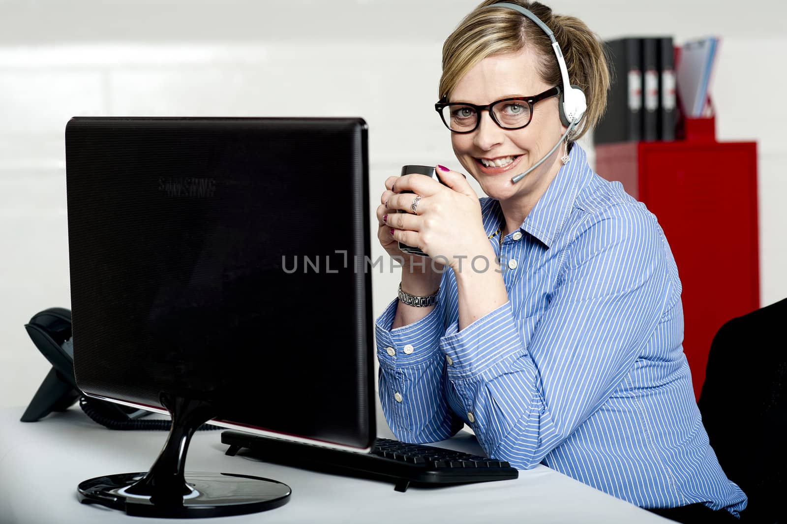 Aged businesswoman sipping coffee during break. At work desk