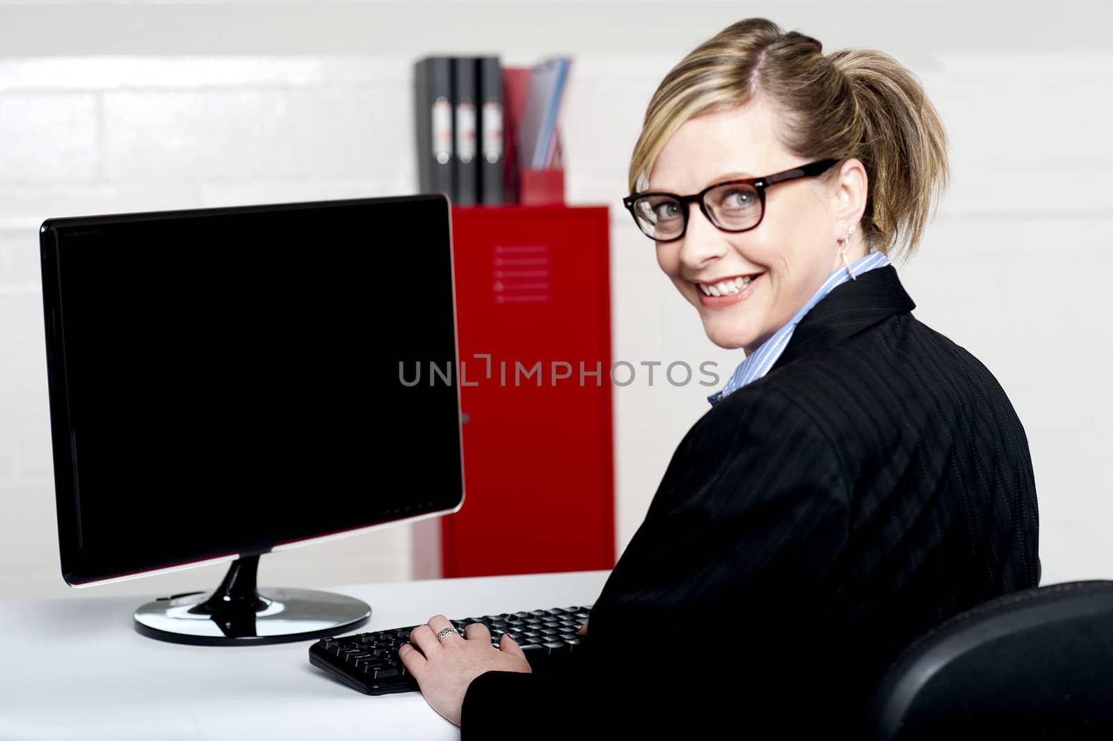 Business lady turning back and smiling at camera while typing on keyboard