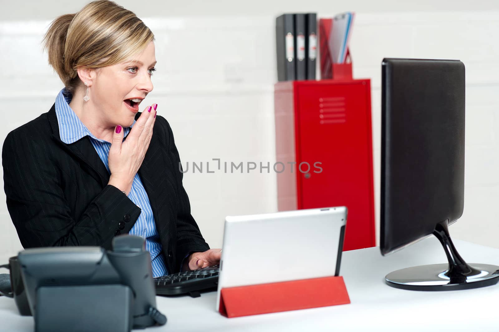 Surprised female secretary looking at lcd screen. Indoors office shot