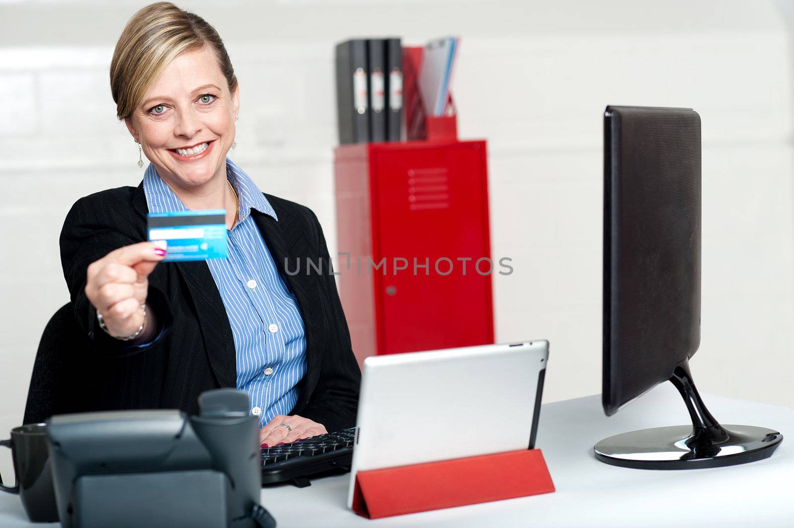 Beautiful corporate woman holding credit card and showing it to camera