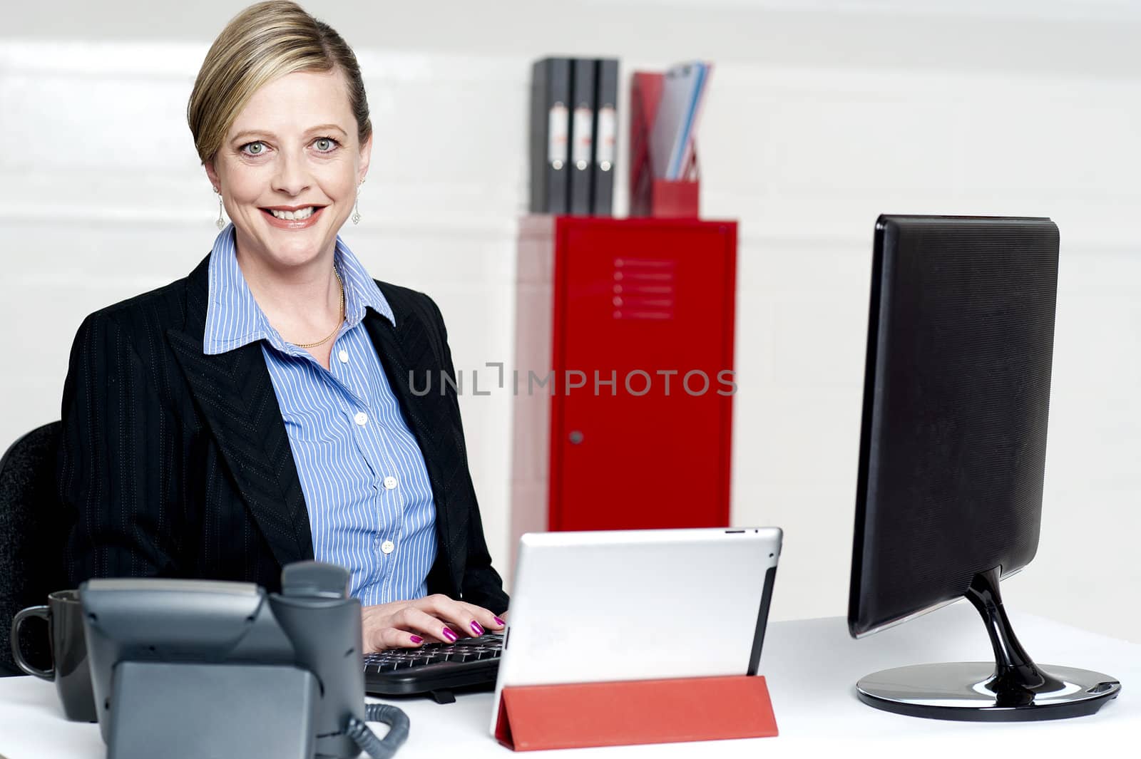 Cheerful female secretary typing document on computer. Working in office