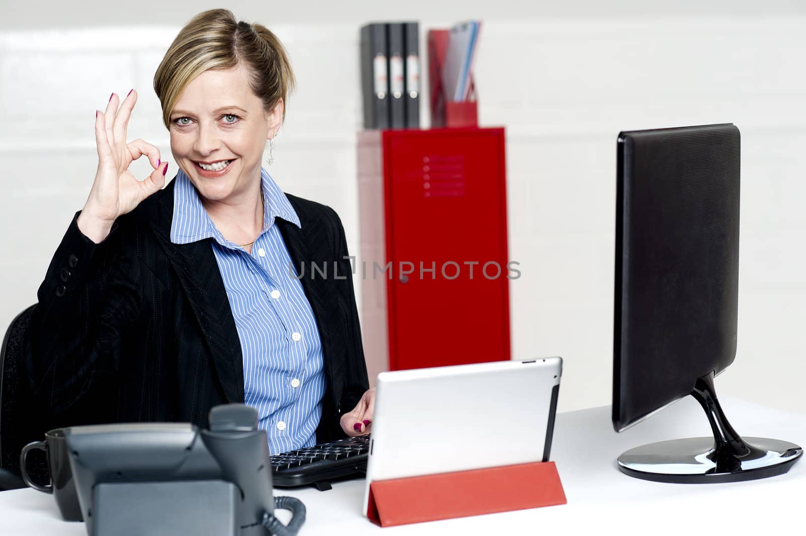 Senior female executive showing excellent gesture while sitting at work desk