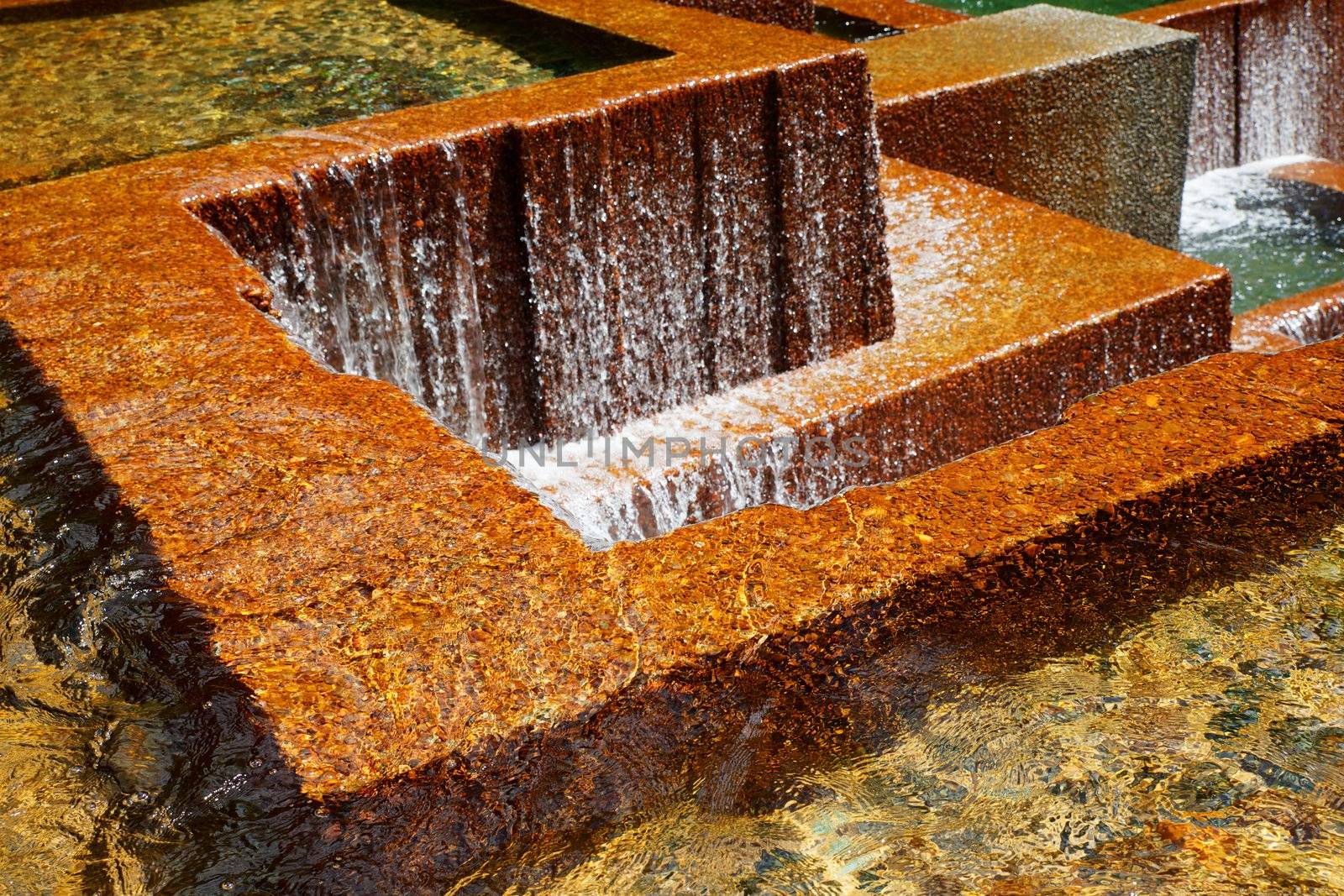 Multiple pools with water falls over golden concrete walls