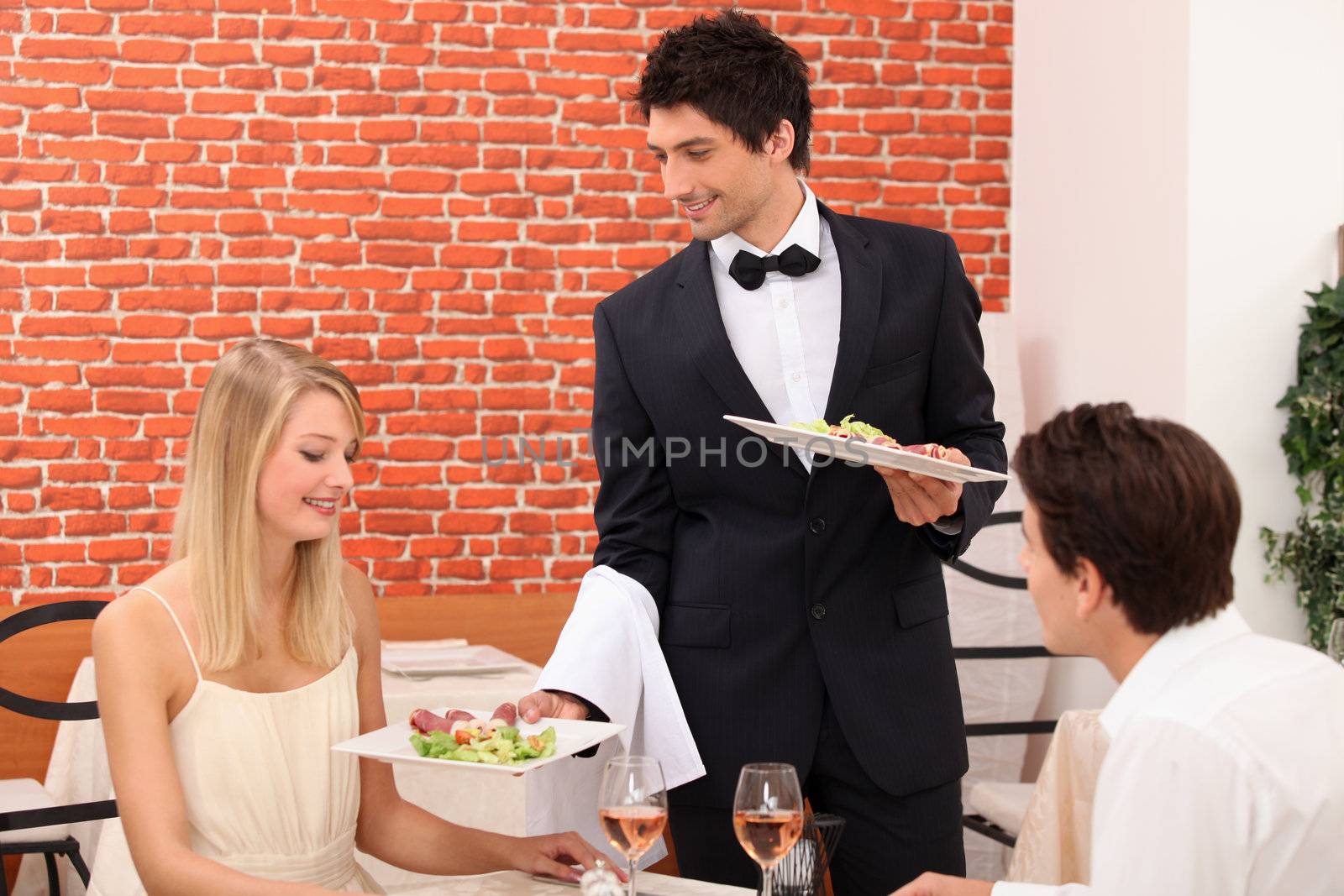Waiter serving plate of food by phovoir
