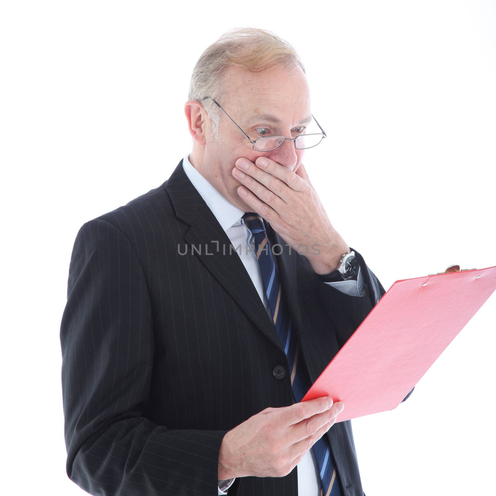 Appalled middle-aged businessman reading a report and covering his mouth with his hand in shock 