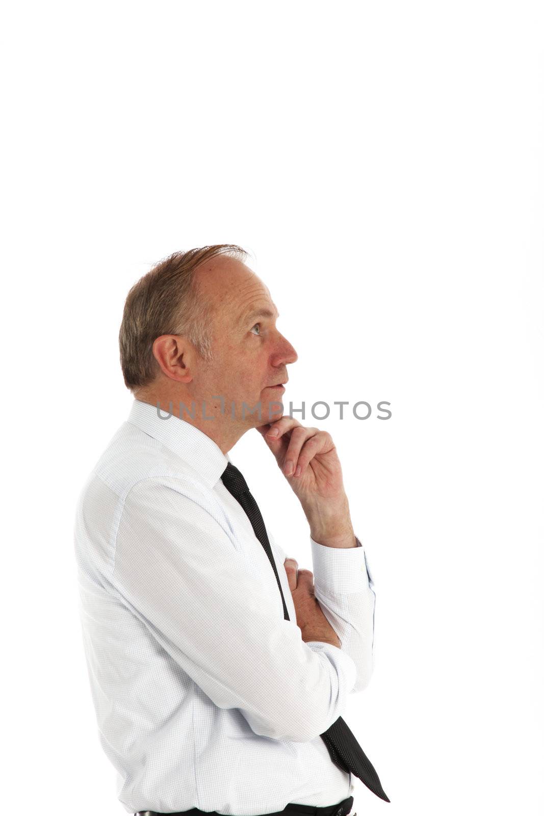 Businessman standing in profile with his chin resting on his hand in deep contemplation Businessman standing in profile with his chind resting on his hand in deep contemplation 