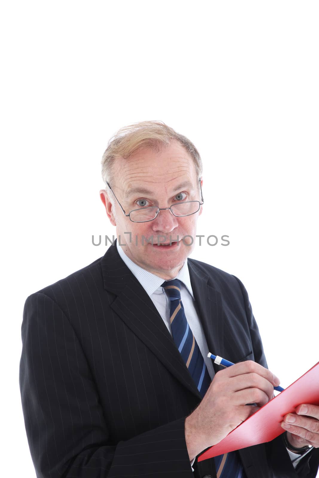 Attentive businessman peering over the top of his spectacles and listening expectantly while taking notes Attentive businessman peering over the top of his spectacles and lstening expectantly while taking notes 