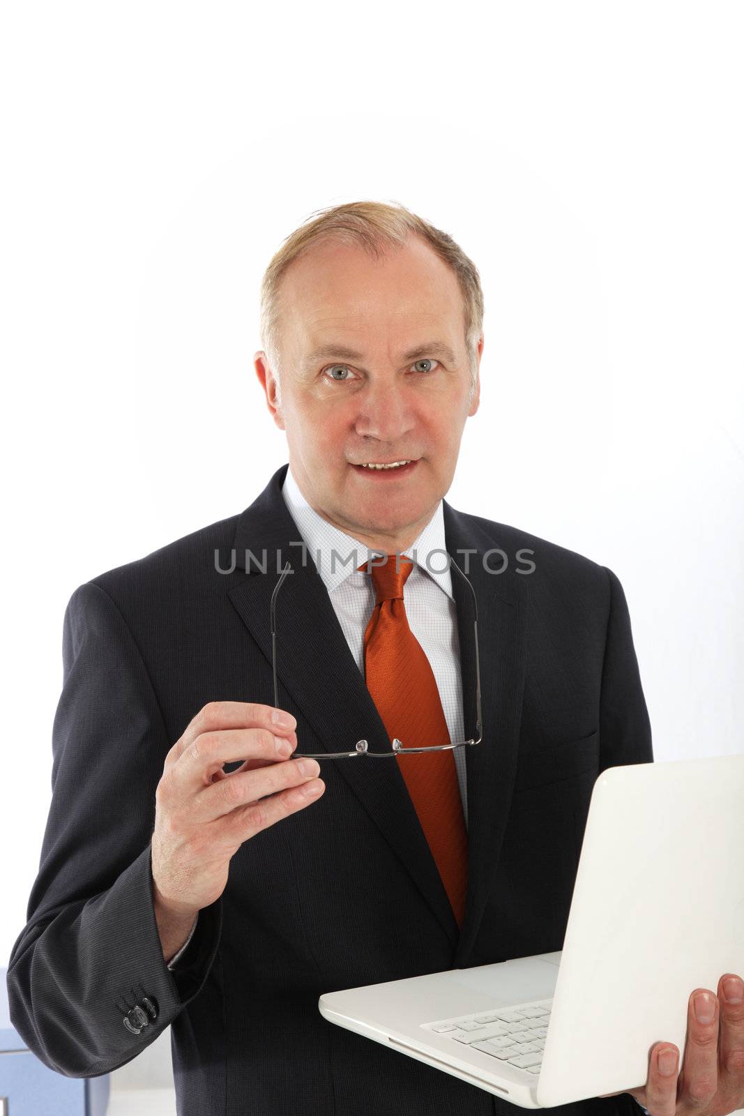 Charismatic middle-aged businessman with an engaging expression standing with his laptop balanced on his arm Charismatic businessman with an engaging expression standing with his laptop balanced on his arm 