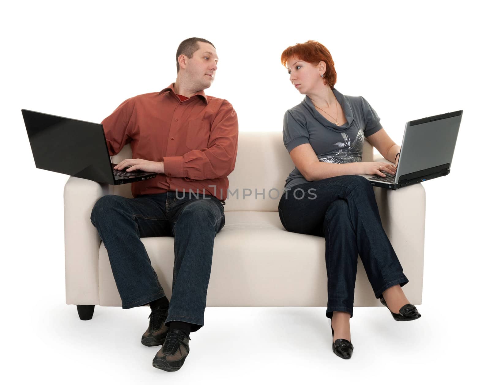 Husband and wife sitting on the couch with laptops