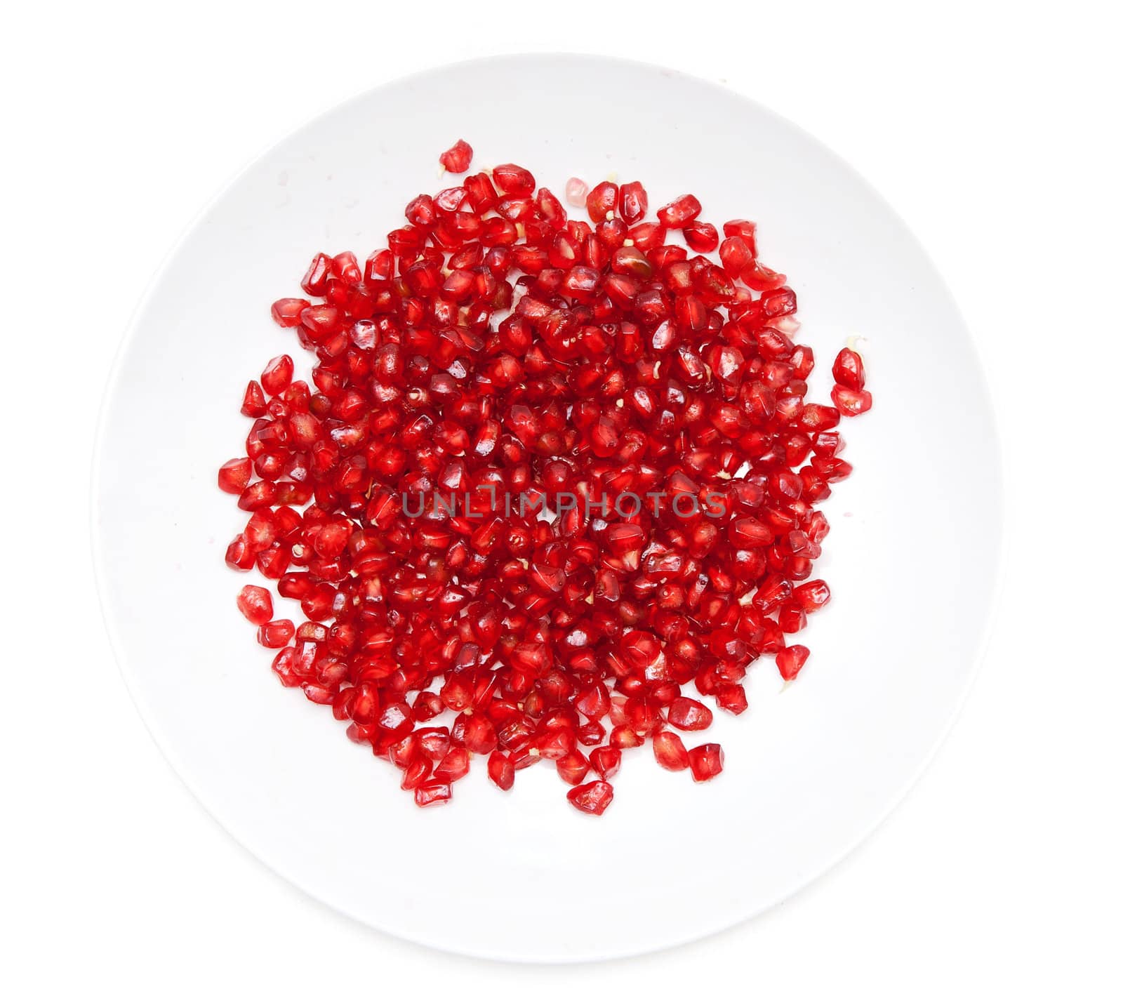 Red pomegranate seeds on a plate on a white background