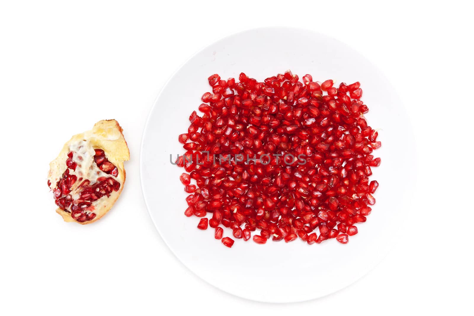 Red pomegranate seeds on a plate, and peeled fruit
