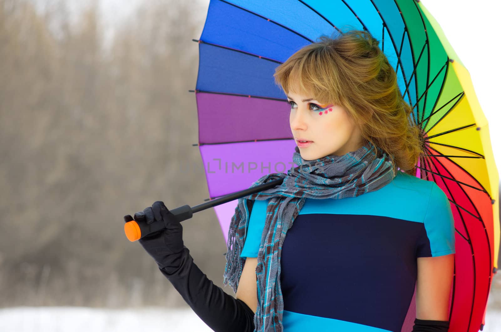 Young woman with multicolor umbrella at winter forest