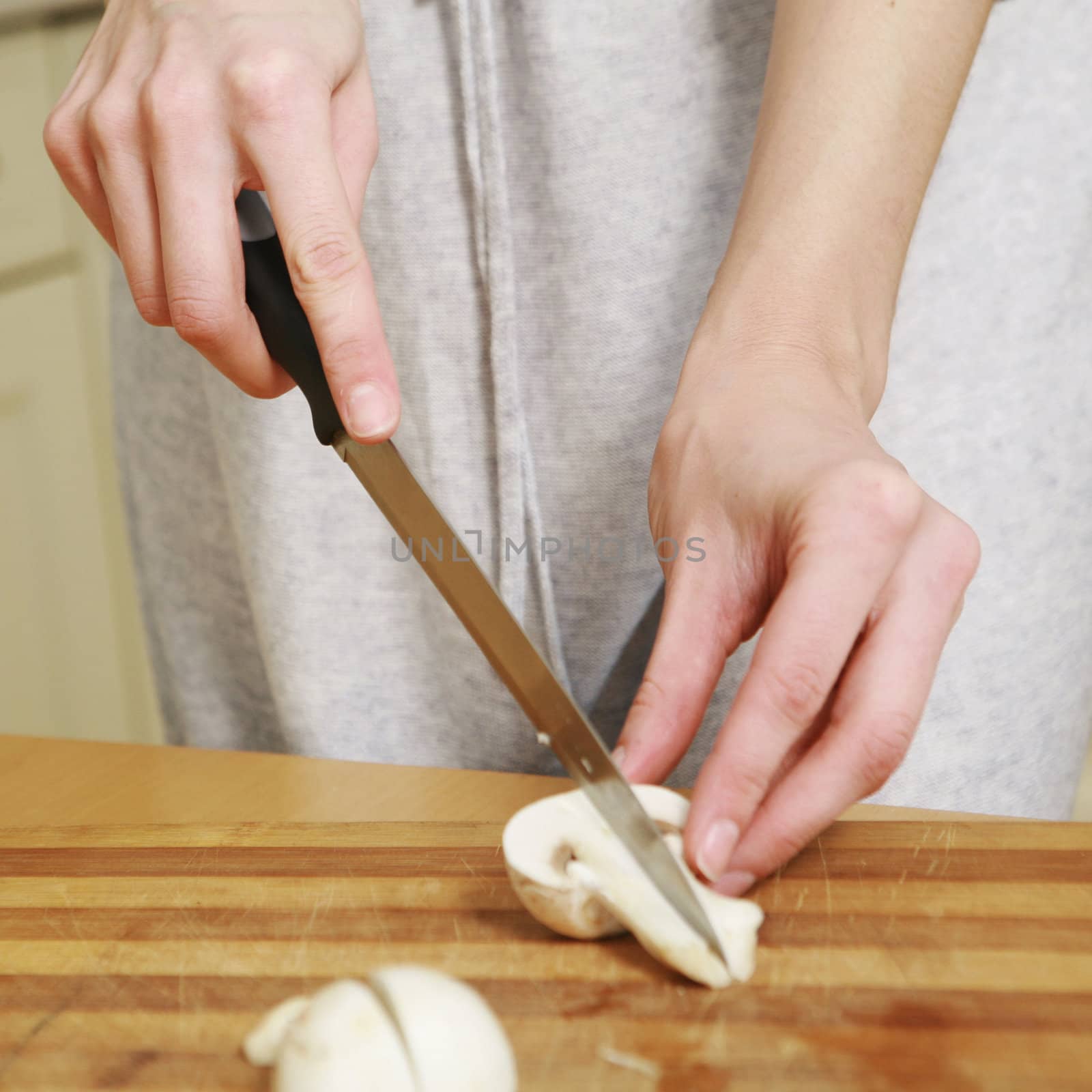 An image of hands cutting white mushrooms