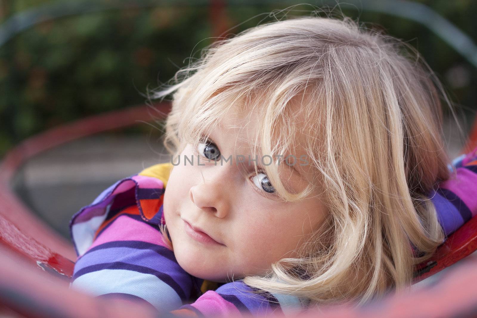 A cute girl resting on a climbing frame in a playground