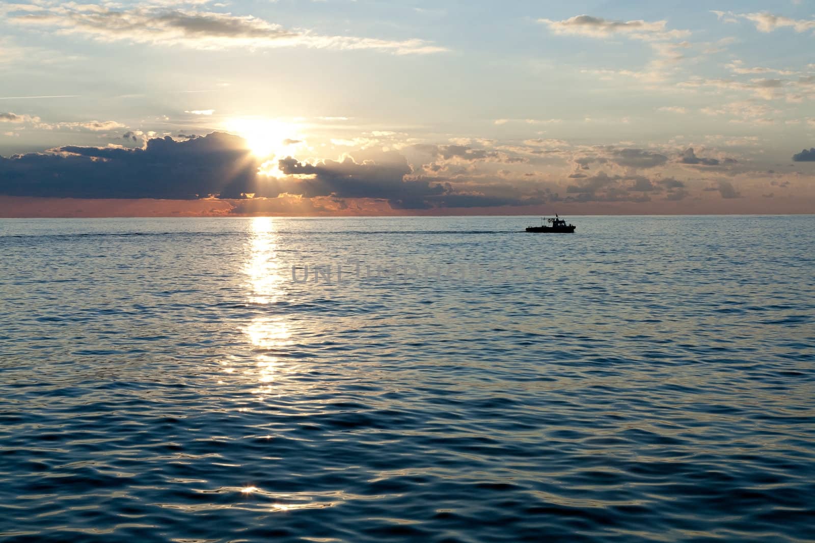 Small boat sailing on the sea at sunset and clouds