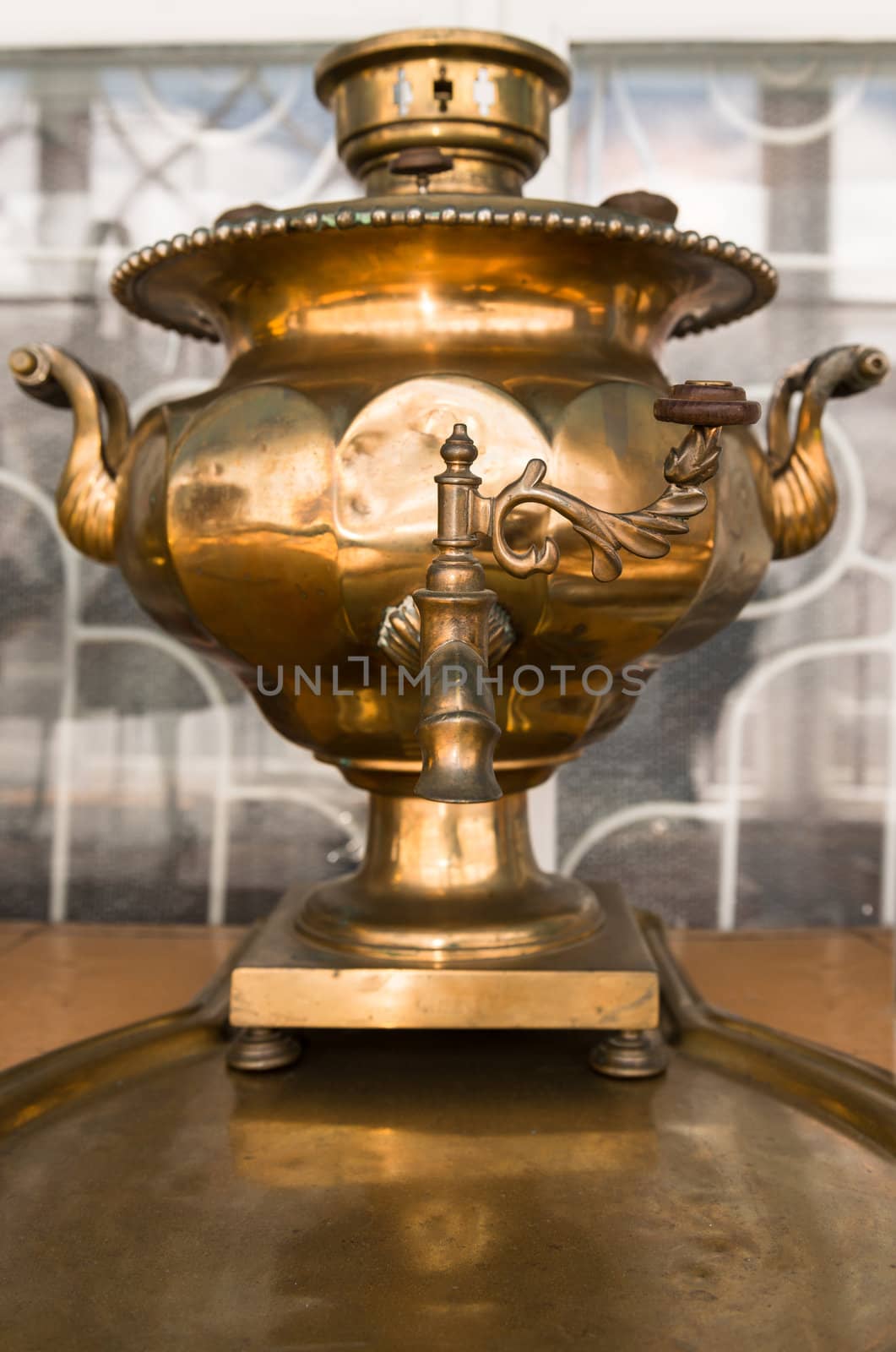 Old russian bronze tea samovar on tray. Selective focus on the tap handle.