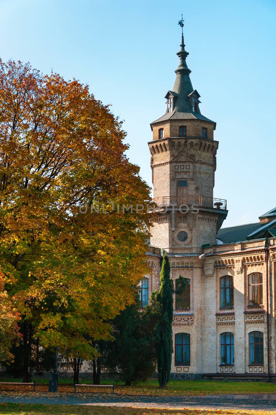 Vintage brick building in autumnal park with blue clean sky