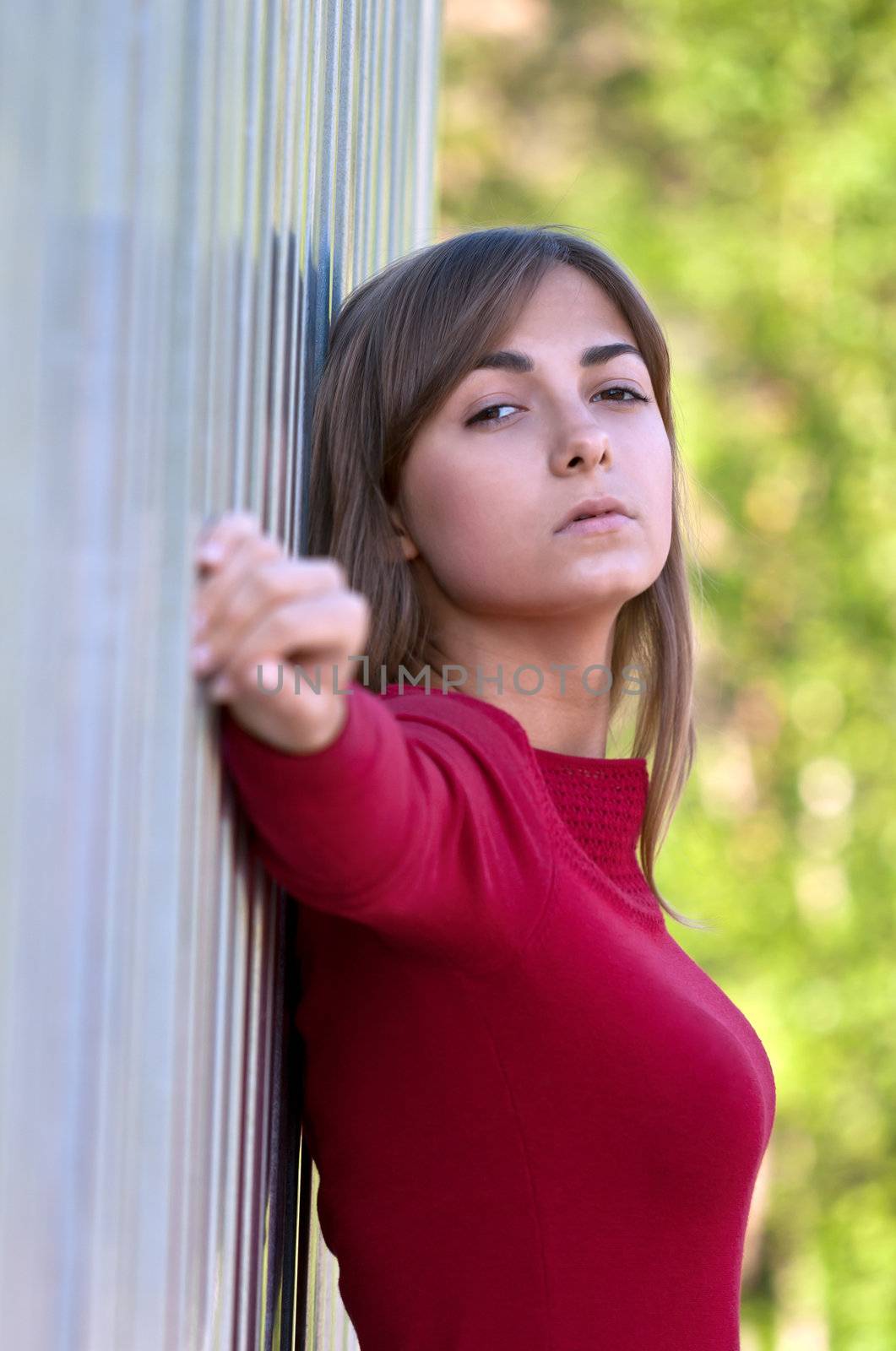 Portrait of a beautiful young girl in a red dress against the iron wall and timber
