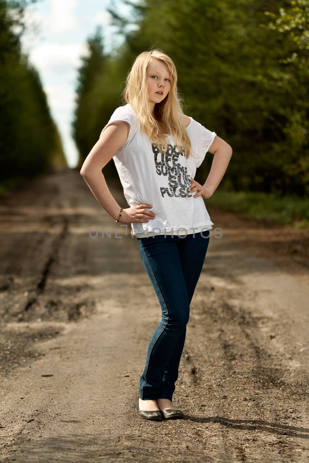 beautiful blonde in a white dress and jeans on the road in the woods