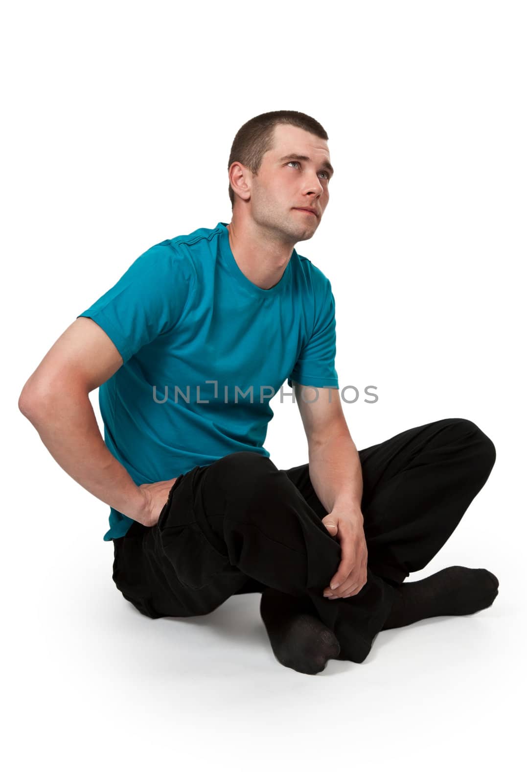 man in a blue dress sitting in a lotus position on a white floor