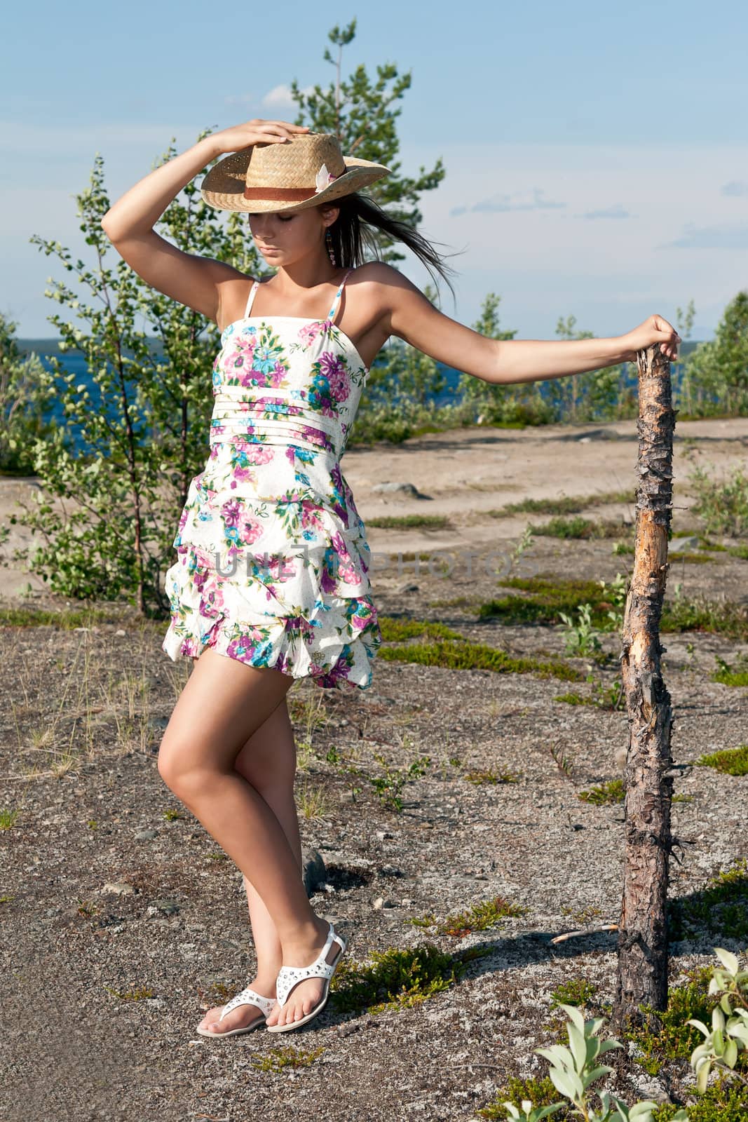 girl in a straw hat next to the dry pine