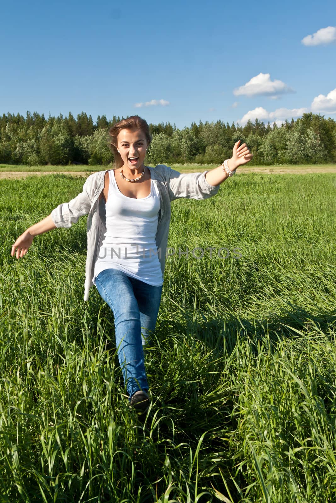 beautiful young girl goes on the green grass