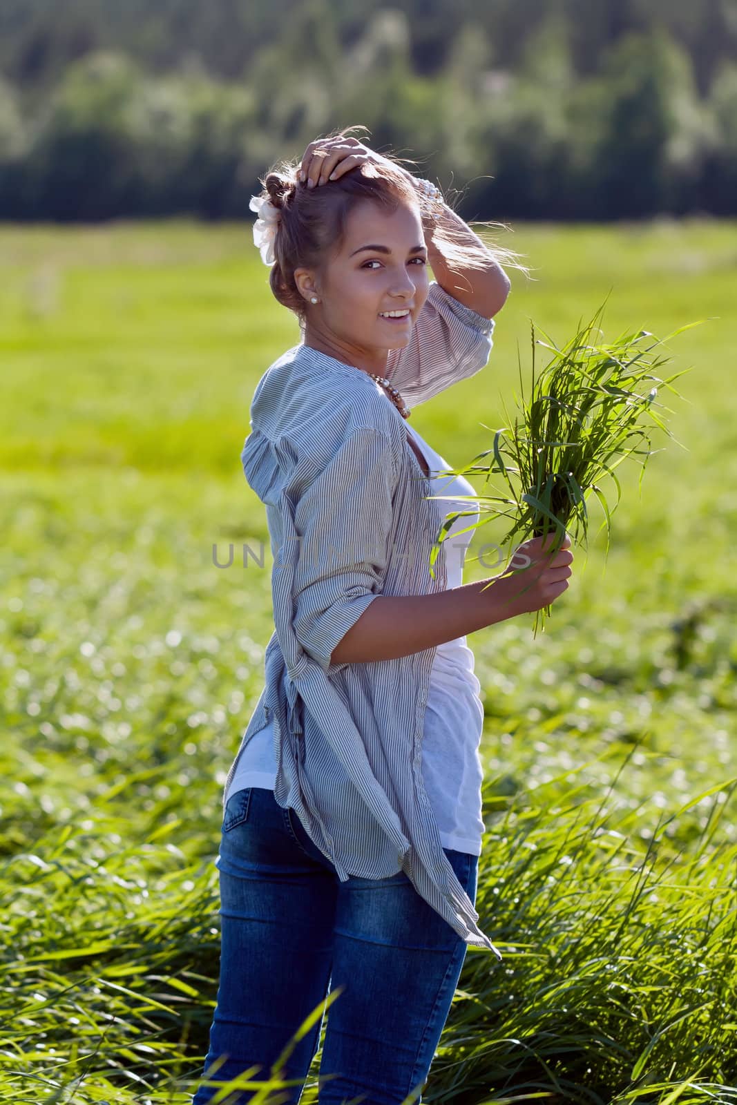 girl with a bundle of green grass in a meadow