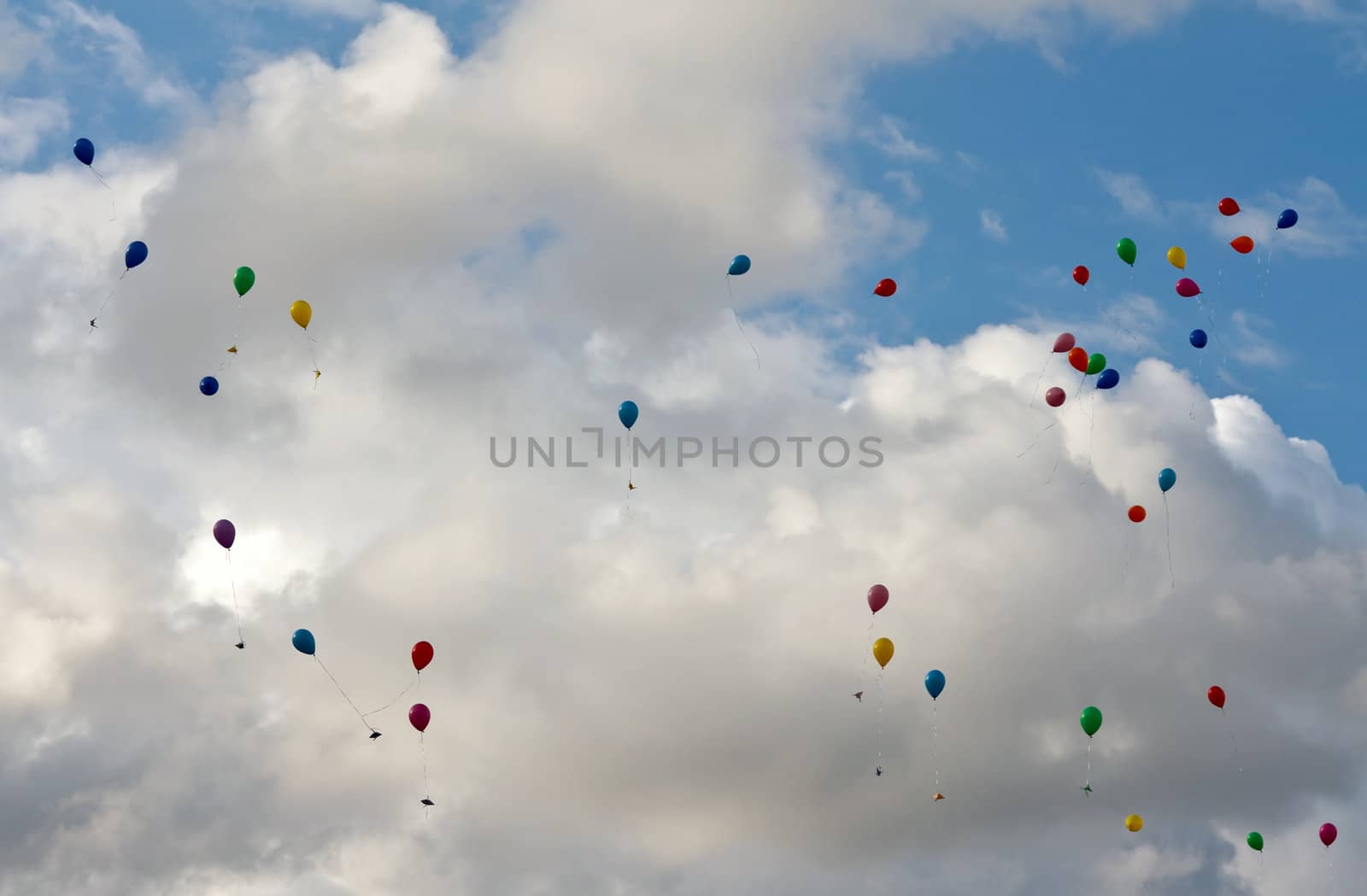 colored balloons flying in the sky with clouds
