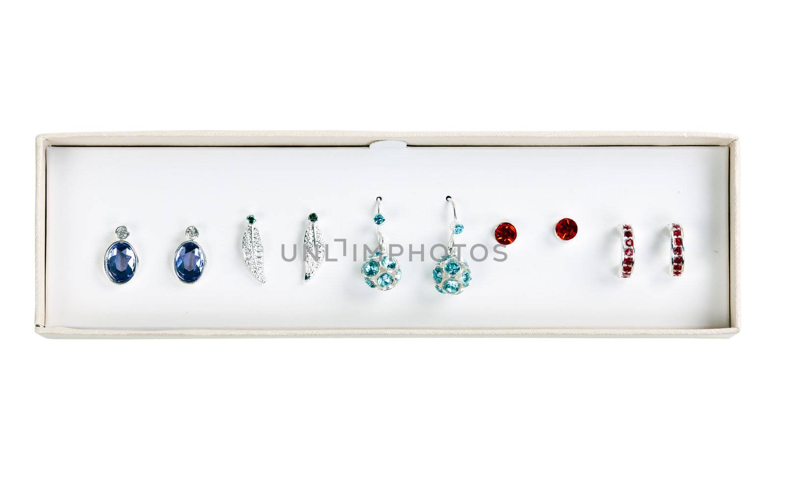 five pairs of earrings with stones in a cardboard box on a white background